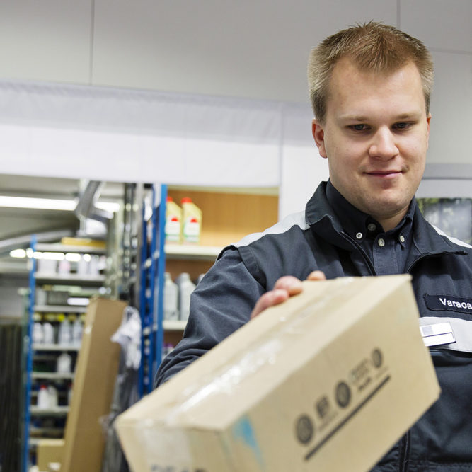 Varaosamyyjä tutkii pahvipakettia.