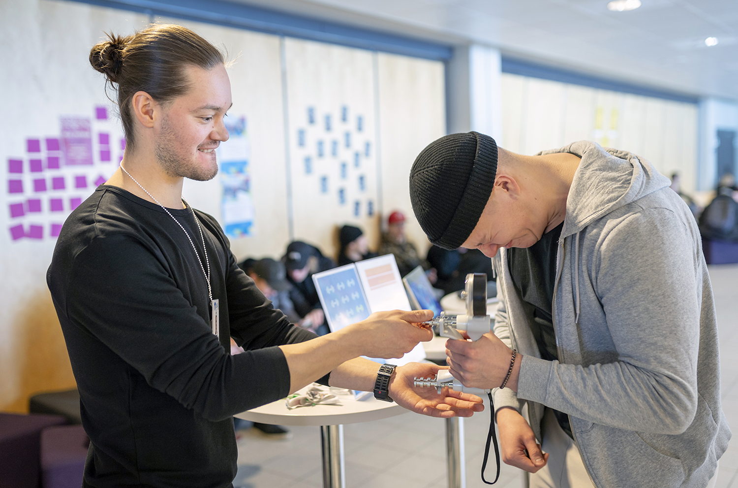 Mies mittaa puristusvoima, toinen mies opastaa ja tarkkailee vieressä.