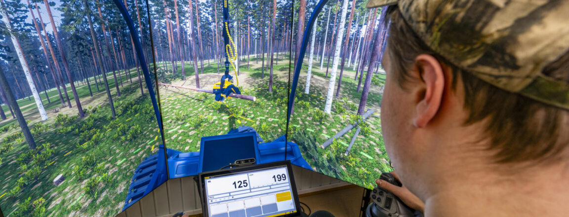 Henkilö istuu metsäkonesimulaattorissa. Hänen edessään on suuri kaareva näyttö, joka näyttää metsämaiseman, ja hän ohjaa laitetta joystickin avulla.