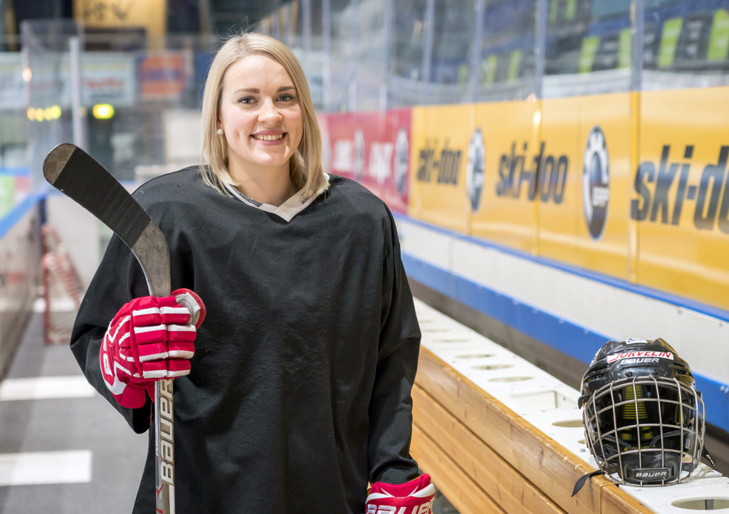 Nuori nainen jääkiekkovarusteissa.