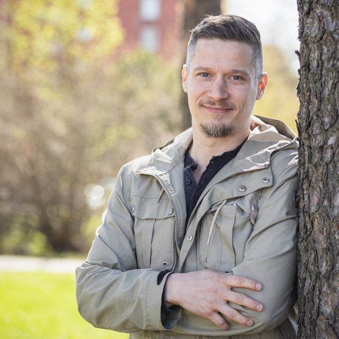 Parrakas mies nojaa mäntyyn.