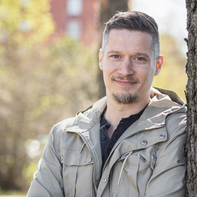 Parrakas mies nojaa mäntyyn.