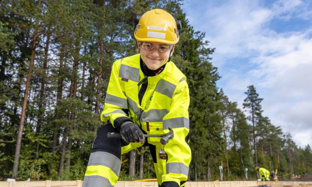 Keltaisiin työvaatteisiin ja kypärään pukeutunut mies pitää vasaraa kädessään.