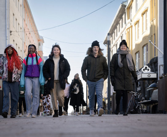 Viisi nuorta kävelevät Oulun keskustassa Rotuaarilla.