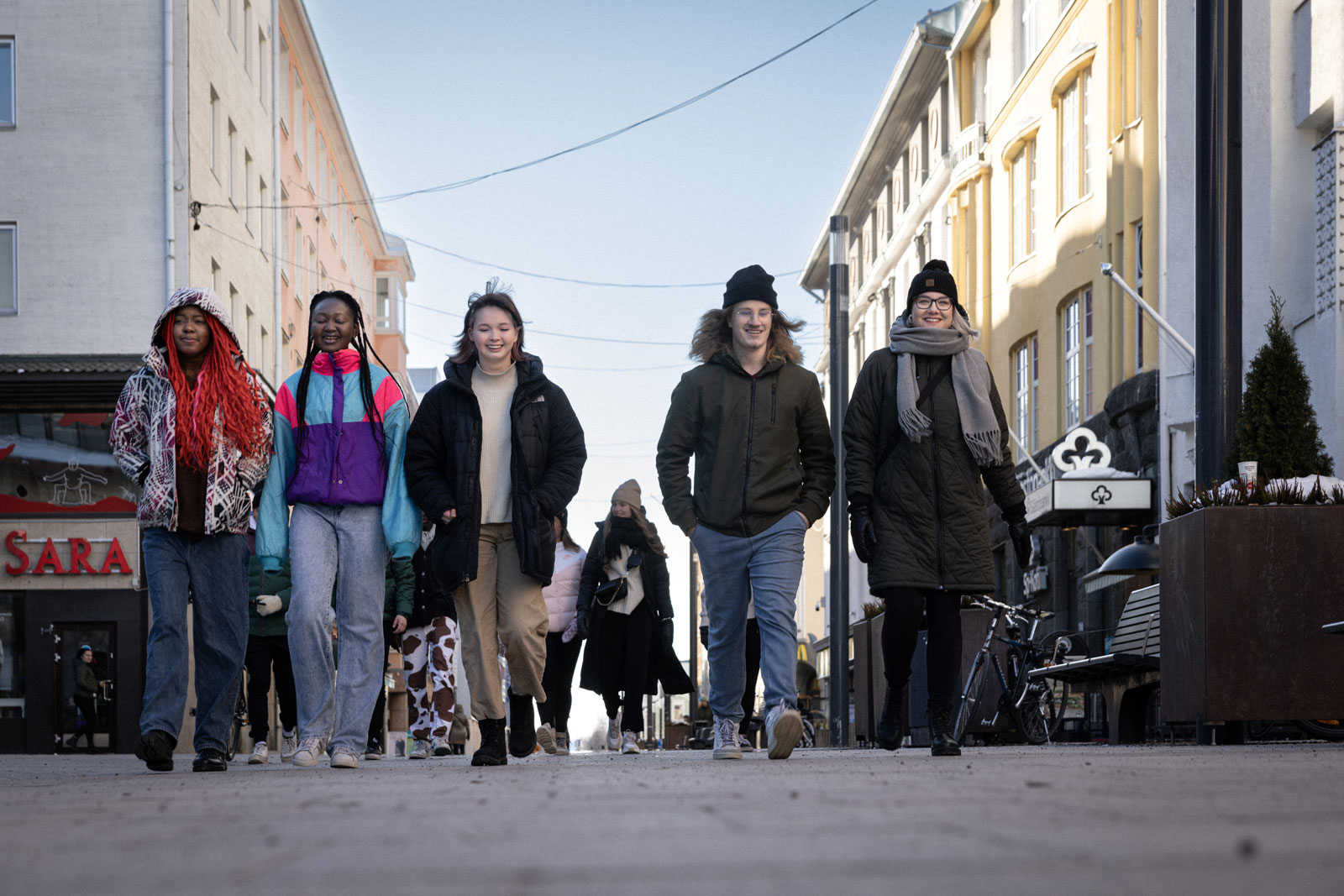 Viisi nuorta kävelevät Oulun keskustassa Rotuaarilla.
