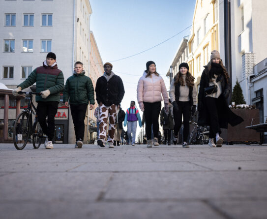 Joukko nuoria kävelee pihalla rivissä kohti kameraa.