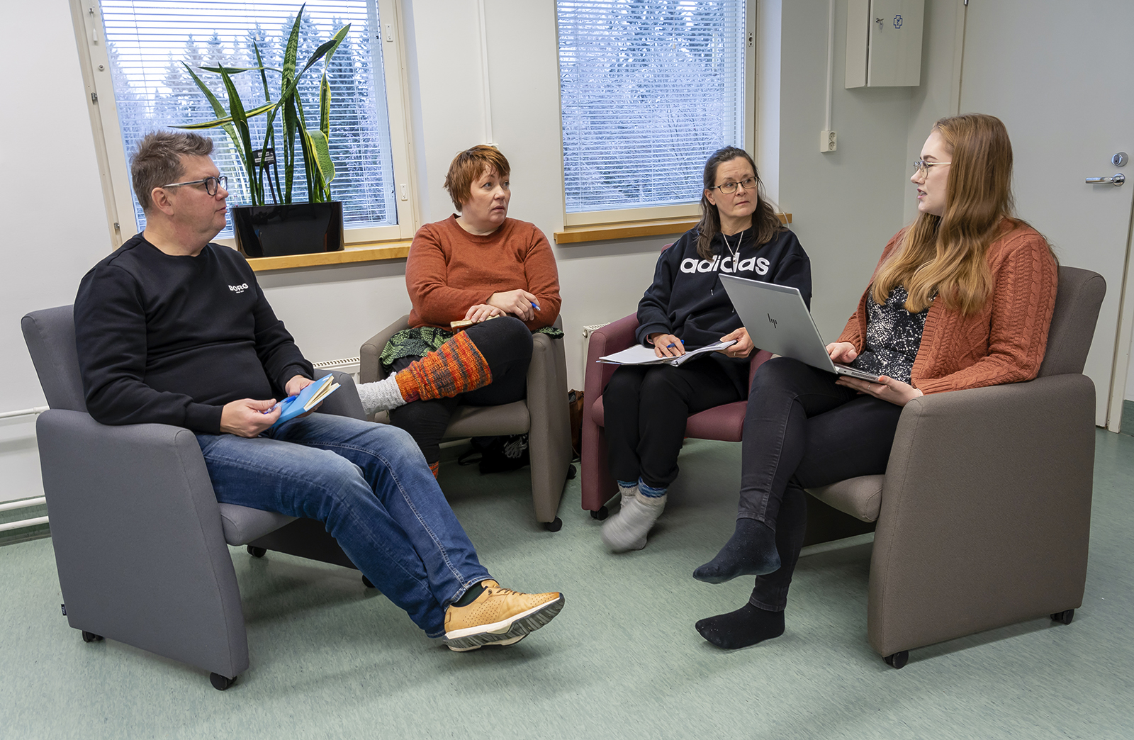 Opettaja Ismo Lindroth ja kolme opiskelijaa istuvat nojatuoleissa ja keskustelevat.