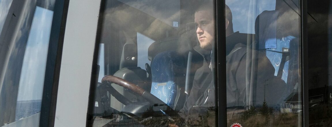 Linja-autonkuljettaja istuu linja-auton kuskin paikalla.