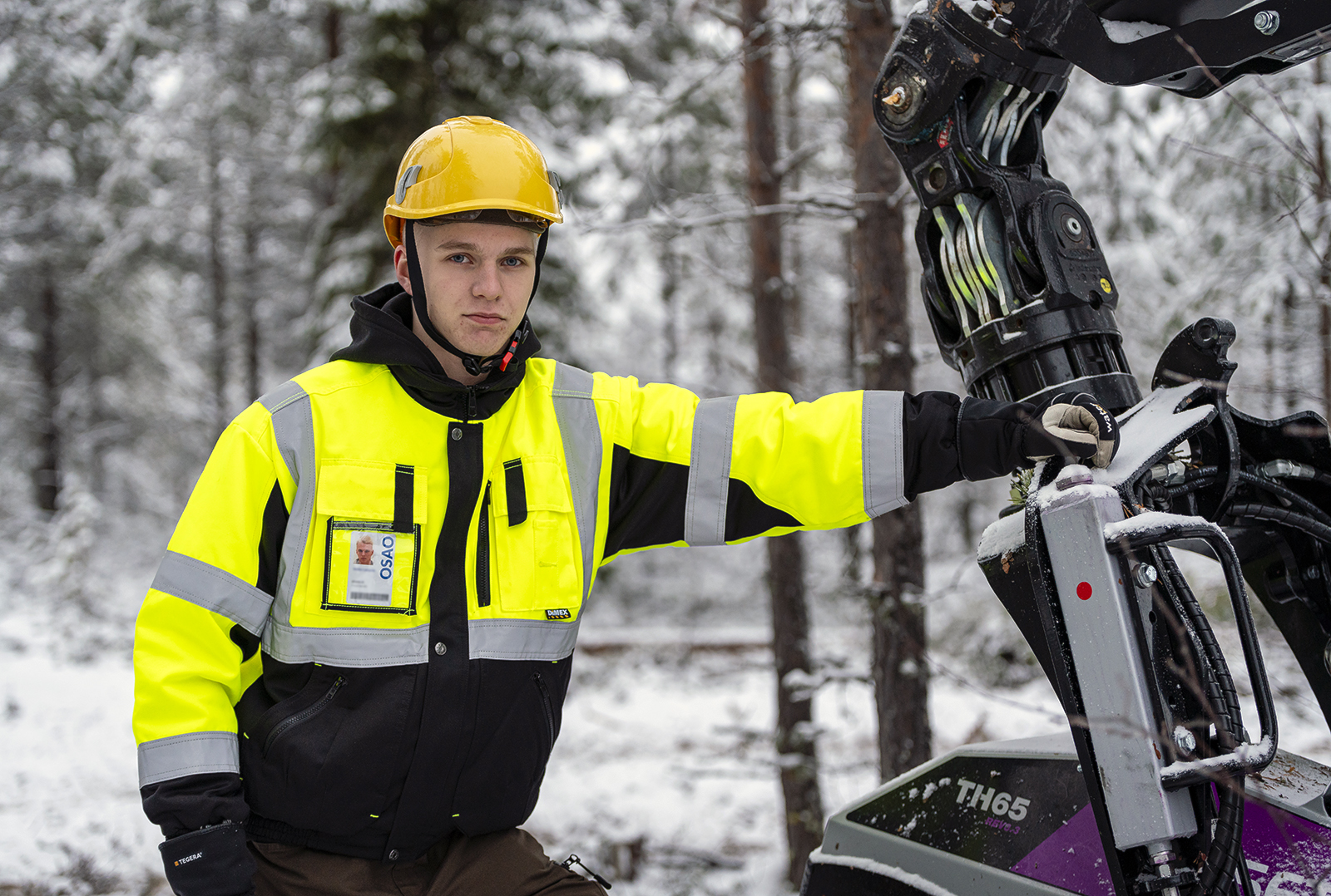 Metsäalaa opiskeleva Veikko Lampela kuvattuna metsätyökoneen vieressä.