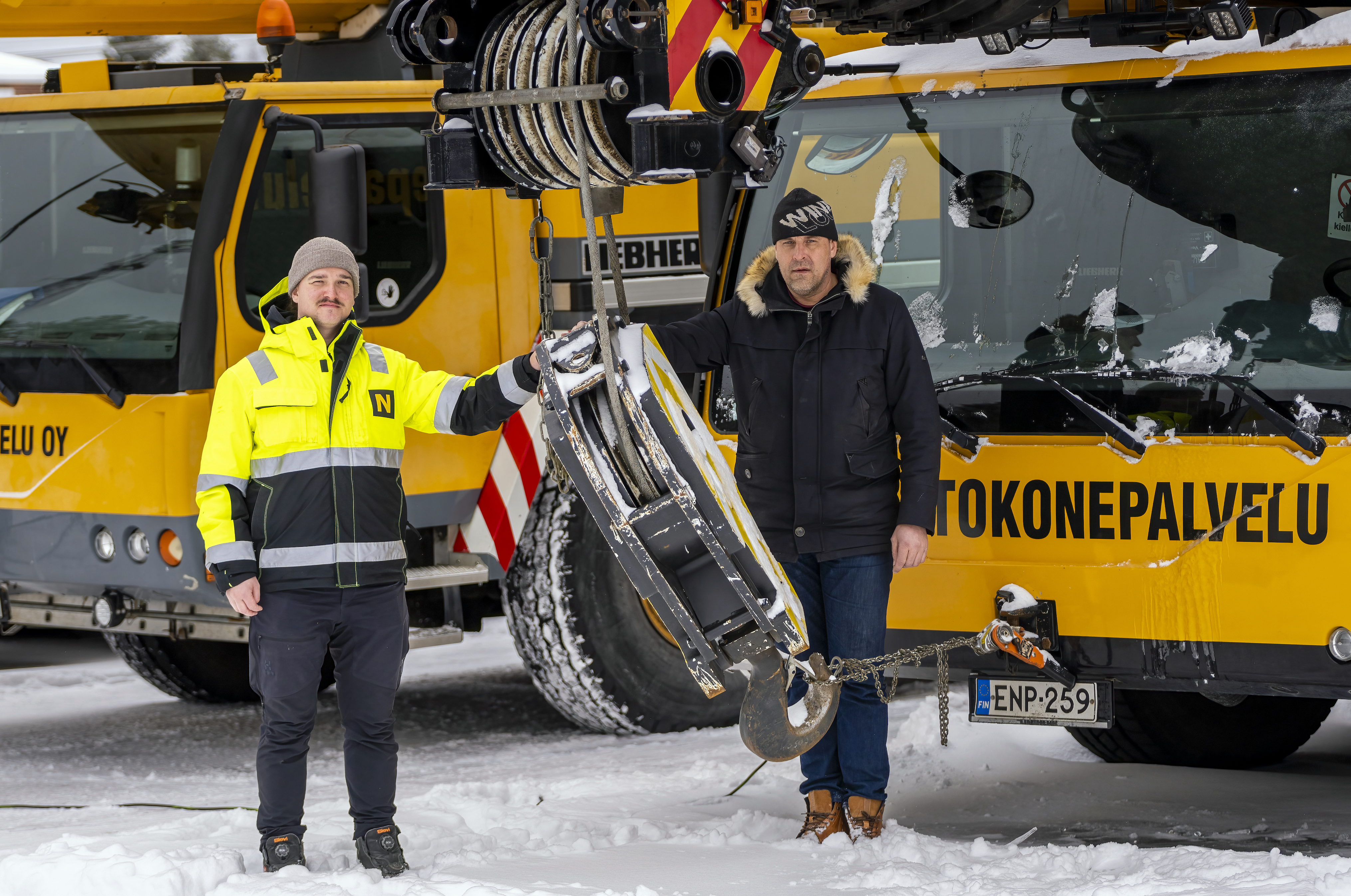 Nostokonepalvelu AT Oy:n Joni Mäkelä ja Sampo Saarijärvi kuvattuna yrityksen keltaisen ajoneuvonosturin edessä.