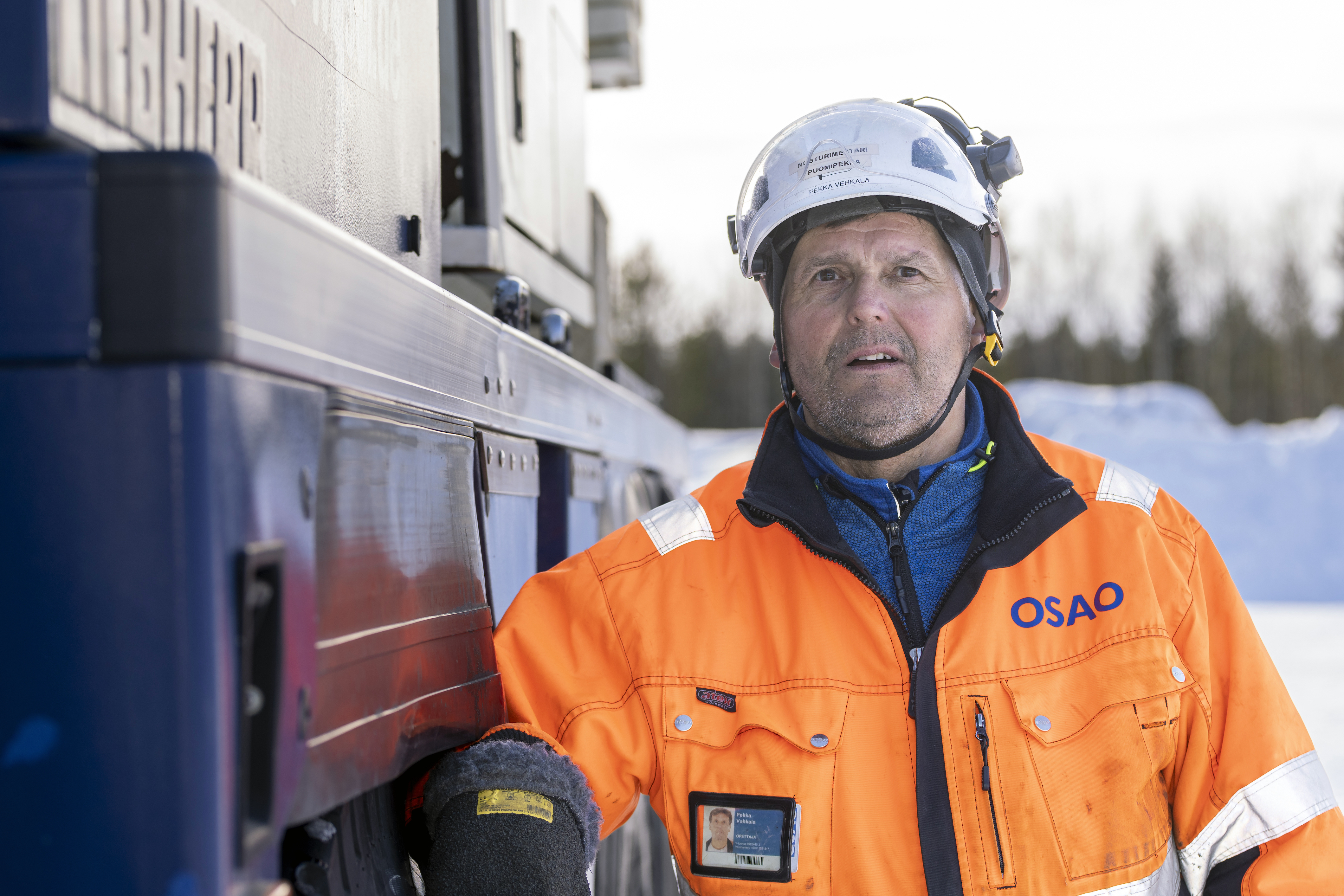 OSAOn opettaja Pekka Vehkala kuvattuna sinisen ajoneuvonosturin edessä.