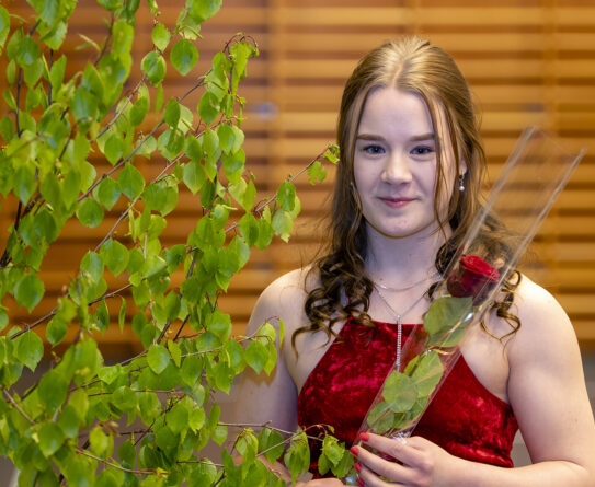 Valmistuva opiskelija Sini Hintsala kädessään ruusu.