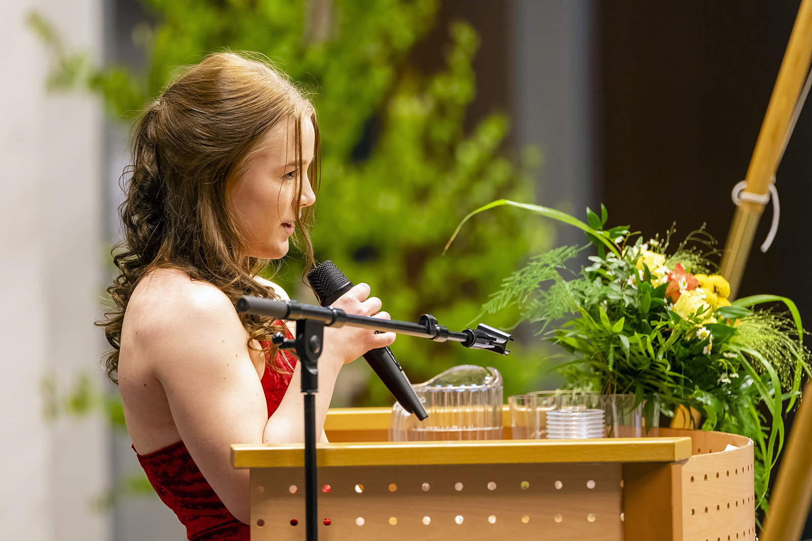 Valmistuva opiskelija Sini Hintsala pitää puhetta kädessään mikrofoni.