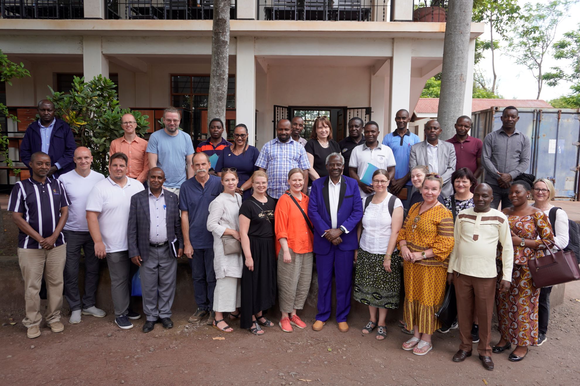 Ryhmäkuva Kilimanjaro VET -hankkeessa mukana olevista suomalaisista, virolaisista ja tansanialaisista henkilöistä ELCT Hai -oppilaitoksen pihalla.
