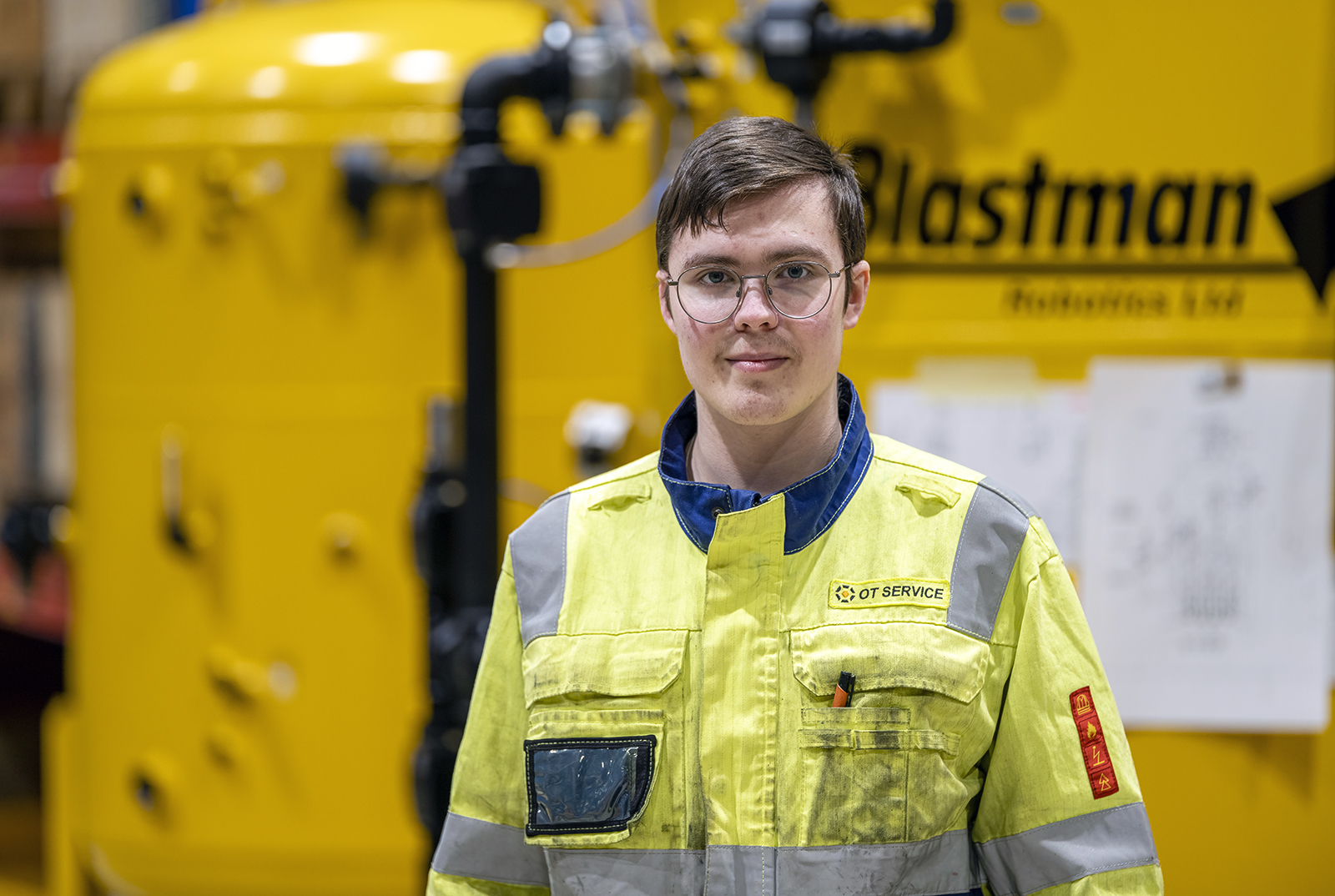 Artturi Ylimäki kuvattuna keltaisessa koneautomaatioasentajan työasussa työhallissa.