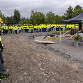 Iso joukko rakennusalan opiskelijoita seisoo rivissä työmaalla.