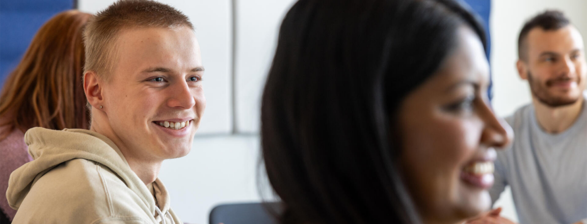 Iloisia ihmisiä istuu huoneessa keskustelemassa.