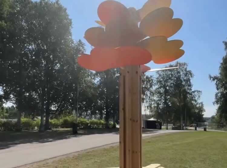 Puinen, puun muotoinen penkki nurmialueella auringonpaisteessa.