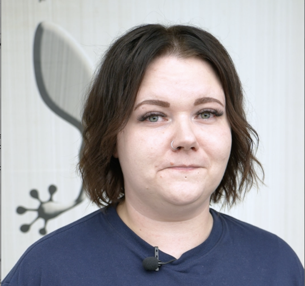 Henkilö seisoo seinän edessä ja katsoo kameraa kohti.