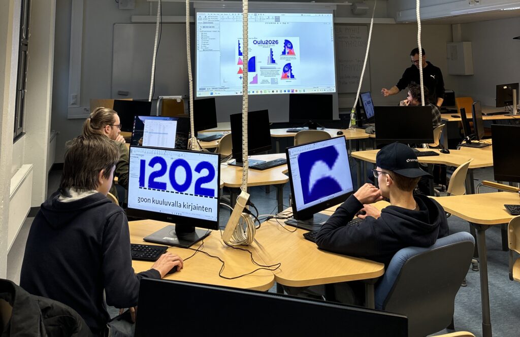 Luokkatila, jossa puualan opiskelijat työskentelevät tietokoneilla mallinnosten parissa. Luokan etuosassa on projektorilla heijastettuna ohjeistusta työskentelyyn.