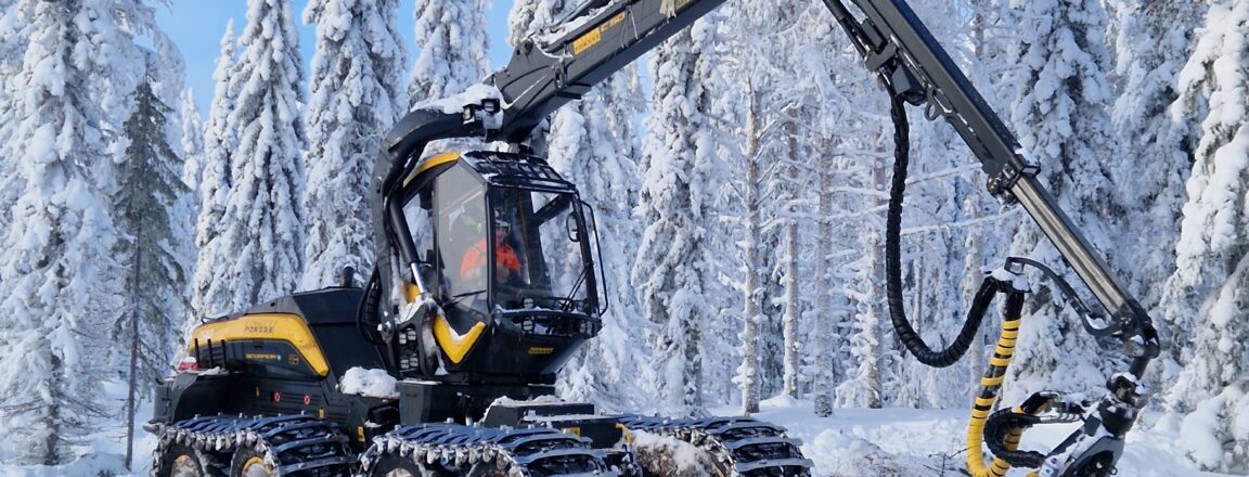Metsäkone työskentelee lumisessa metsässä, ympärillä lumisia puita.