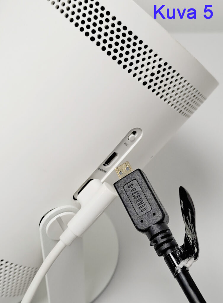 Kuva 5: HDMI-kaapeli ja valkoinen johto liitettyinä valkoiseen laitteeseen, jossa on mustia tuuletusaukkoja.