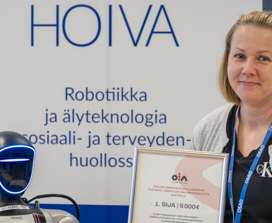 Nainen seisoo robottien vieressä pitäen sertifikaattia, jossa lukee 1. SIJA